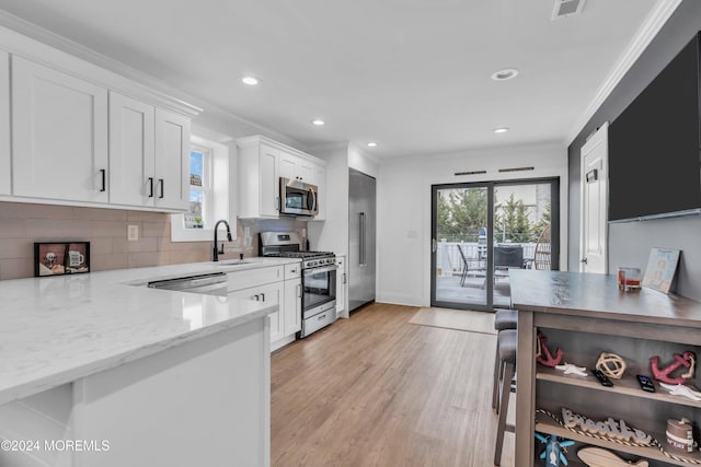 kitchen featuring light stone countertops, appliances with stainless steel finishes, decorative backsplash, crown molding, and white cabinetry