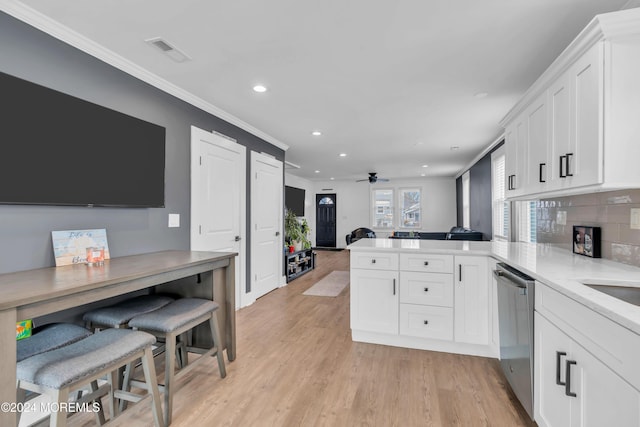 kitchen featuring kitchen peninsula, ornamental molding, ceiling fan, dishwasher, and white cabinets