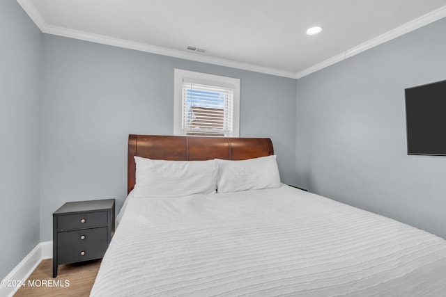 bedroom with hardwood / wood-style floors and ornamental molding