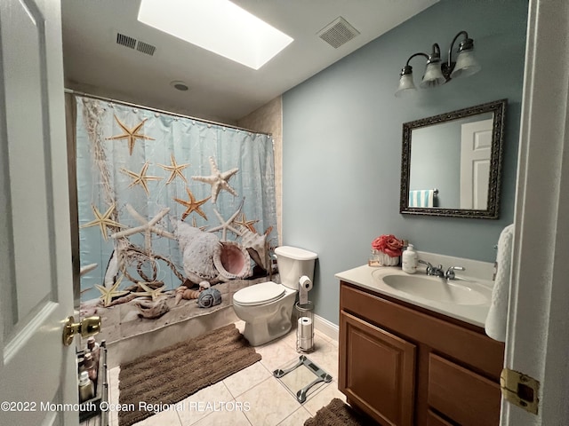 bathroom featuring a skylight, tile patterned flooring, toilet, vanity, and a shower with shower curtain