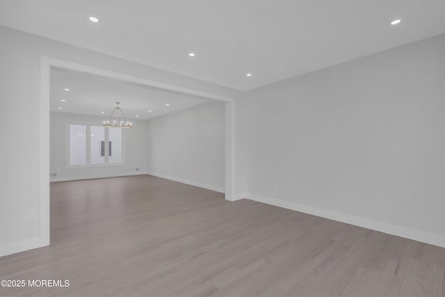 unfurnished room with light hardwood / wood-style floors and a notable chandelier