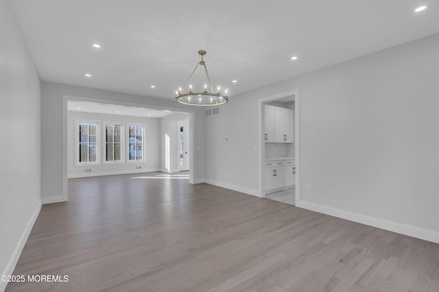 spare room with light wood-type flooring and an inviting chandelier