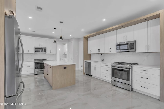 kitchen featuring decorative backsplash, stainless steel appliances, decorative light fixtures, white cabinets, and a center island