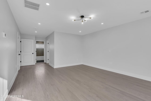 empty room featuring an inviting chandelier and light wood-type flooring