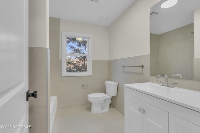 bathroom featuring tile patterned flooring, vanity, toilet, and tile walls