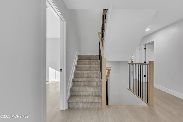 stairway featuring hardwood / wood-style flooring and vaulted ceiling