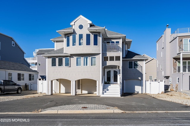 view of front of house featuring a balcony, a gate, fence, and roof with shingles