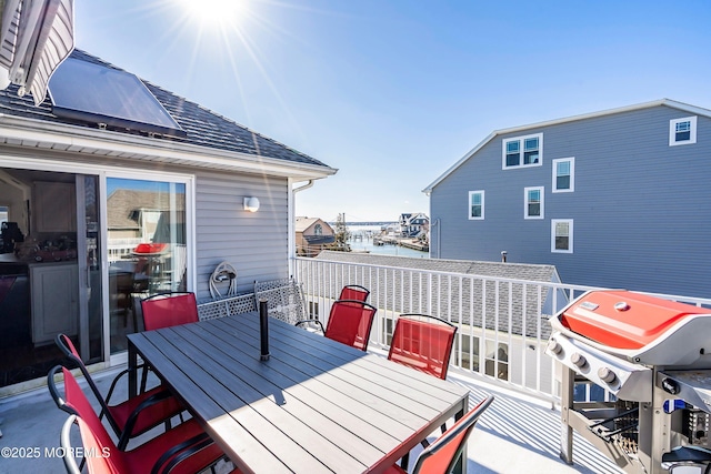 wooden terrace featuring outdoor dining area, a water view, and area for grilling