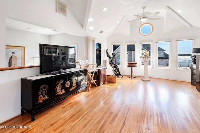 living room with high vaulted ceiling, hardwood / wood-style flooring, visible vents, and baseboards