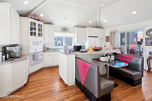 kitchen with vaulted ceiling, white appliances, light wood finished floors, and white cabinets