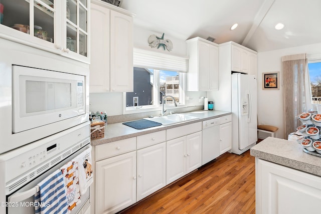 kitchen with light countertops, glass insert cabinets, white cabinetry, a sink, and white appliances