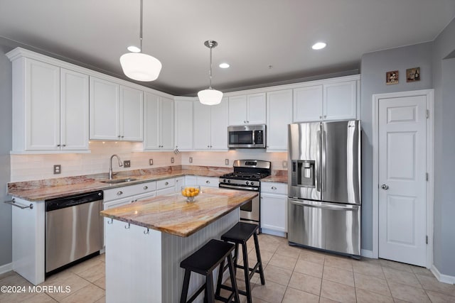 kitchen featuring white cabinetry, a center island, light stone countertops, light tile patterned flooring, and appliances with stainless steel finishes