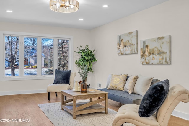 living room featuring a healthy amount of sunlight, light wood-type flooring, and an inviting chandelier