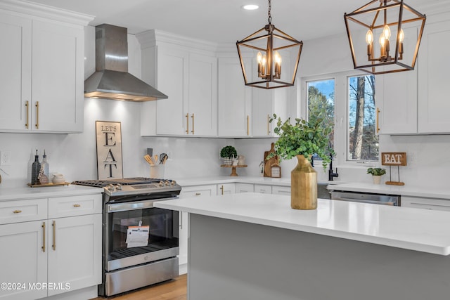 kitchen featuring white cabinetry, wall chimney exhaust hood, hanging light fixtures, and appliances with stainless steel finishes