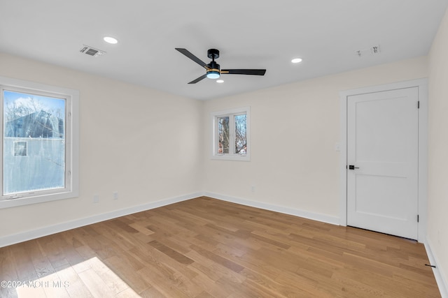 empty room featuring plenty of natural light, ceiling fan, and light hardwood / wood-style flooring