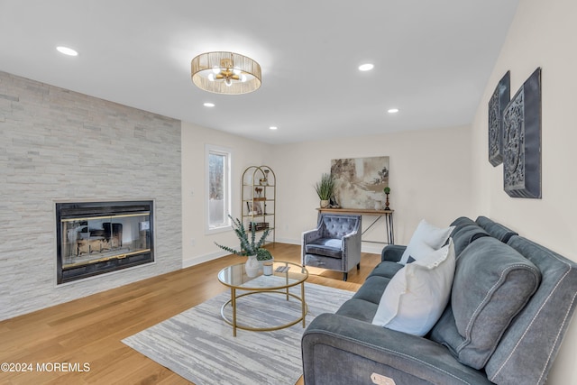 living room featuring hardwood / wood-style flooring, a stone fireplace, and ceiling fan