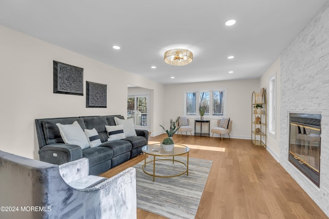 living room featuring a stone fireplace and light wood-type flooring