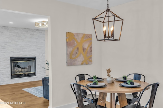 dining room with a fireplace, hardwood / wood-style flooring, and a notable chandelier