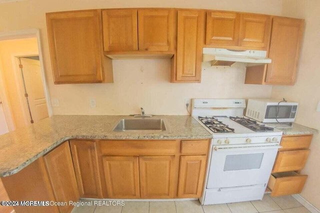 kitchen with light stone counters, sink, light tile patterned flooring, and white appliances