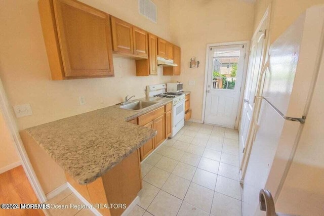 kitchen with kitchen peninsula, light stone countertops, white appliances, sink, and light tile patterned floors