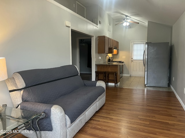 living room with light hardwood / wood-style floors, high vaulted ceiling, and ceiling fan