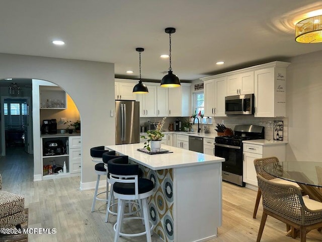 kitchen featuring white cabinets, decorative backsplash, stainless steel appliances, and a kitchen island