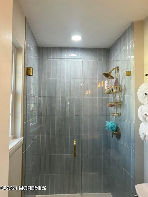 bathroom with a shower with shower door and toilet