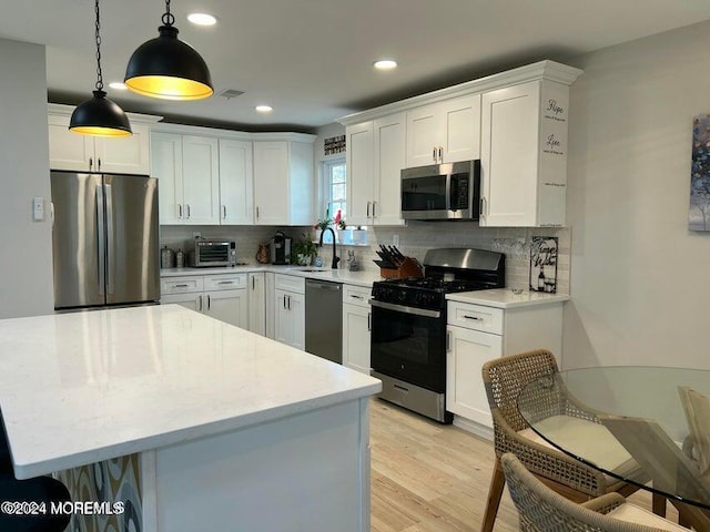 kitchen featuring backsplash, white cabinetry, pendant lighting, and stainless steel appliances