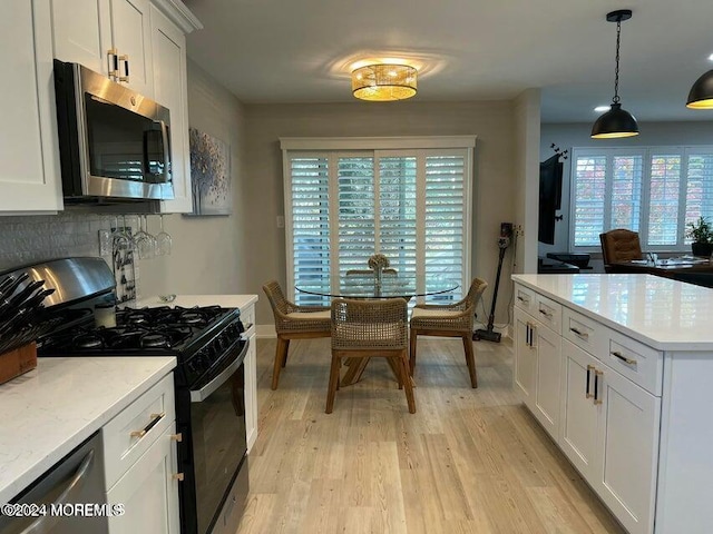 kitchen featuring stainless steel appliances, pendant lighting, white cabinets, light hardwood / wood-style floors, and plenty of natural light