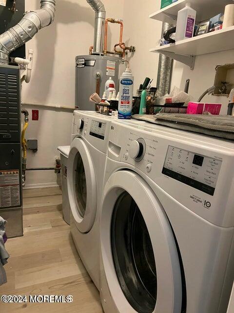 washroom with separate washer and dryer, light hardwood / wood-style floors, and gas water heater