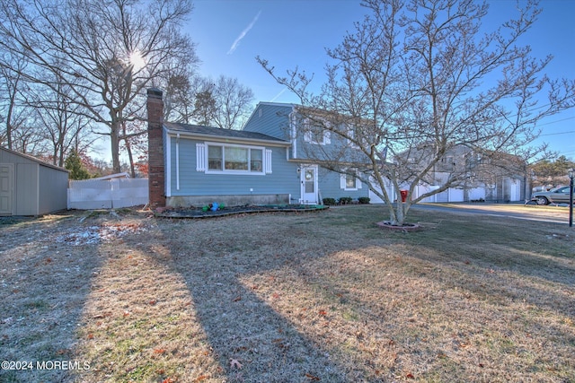 tri-level home with a front lawn and a storage unit