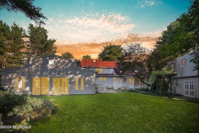 back house at dusk featuring a yard