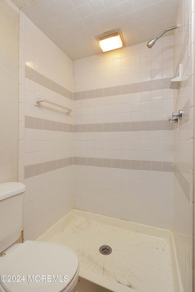 bathroom featuring a tile shower and toilet