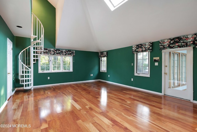 unfurnished living room featuring hardwood / wood-style floors, vaulted ceiling, and a healthy amount of sunlight