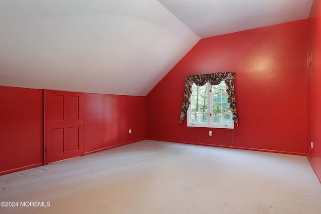 additional living space featuring light colored carpet and vaulted ceiling