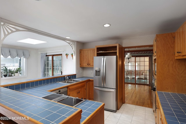 kitchen with stainless steel fridge with ice dispenser, tile counters, light tile patterned floors, and sink