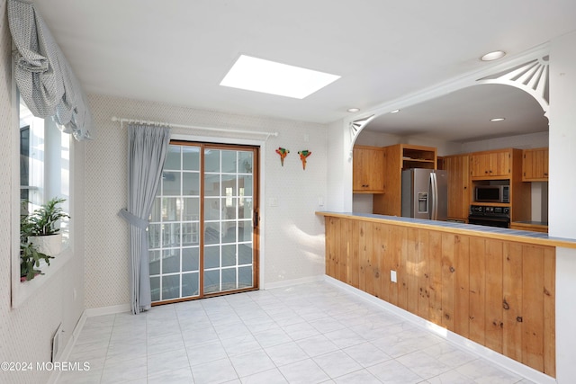 kitchen featuring a skylight, kitchen peninsula, and stainless steel appliances