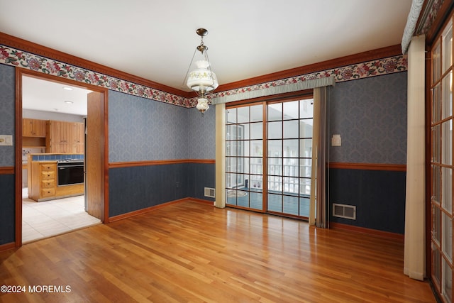 spare room featuring light hardwood / wood-style floors and an inviting chandelier