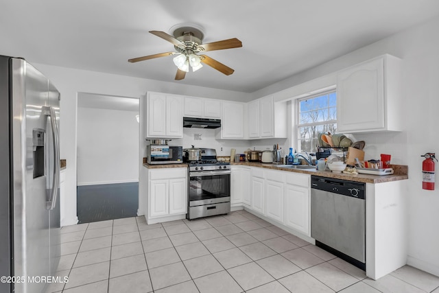 kitchen featuring appliances with stainless steel finishes, ceiling fan, sink, white cabinets, and light tile patterned flooring