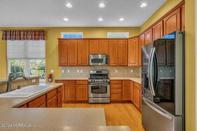 kitchen featuring backsplash, sink, stainless steel appliances, and light hardwood / wood-style flooring