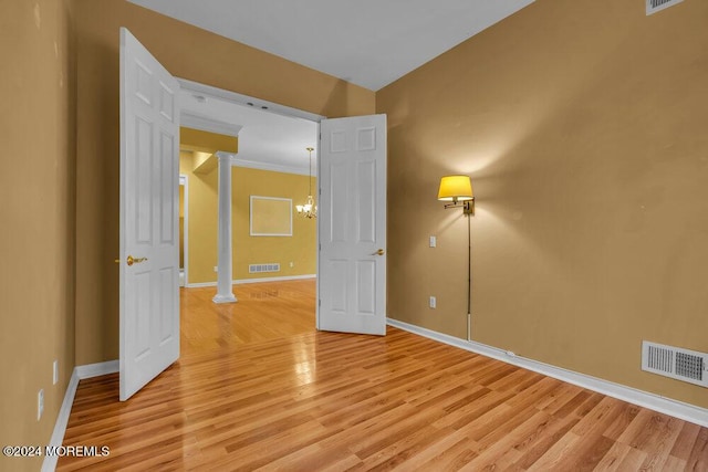 unfurnished bedroom with a chandelier, light hardwood / wood-style flooring, and ornamental molding