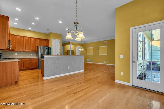 kitchen featuring an inviting chandelier, tasteful backsplash, stainless steel fridge with ice dispenser, light hardwood / wood-style flooring, and pendant lighting