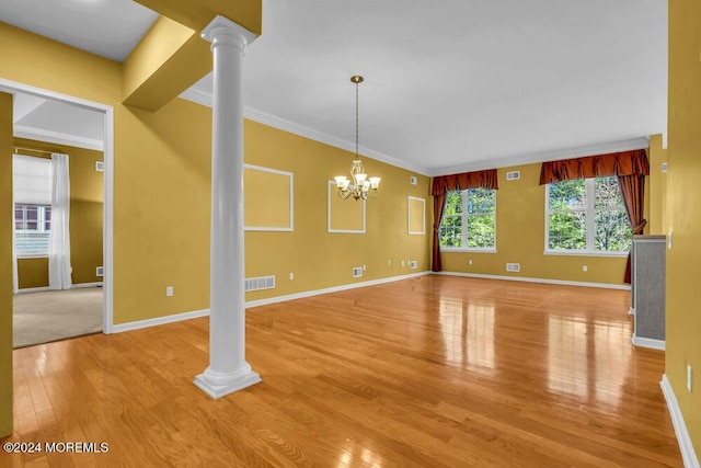 unfurnished living room with a chandelier, light hardwood / wood-style floors, ornate columns, and crown molding