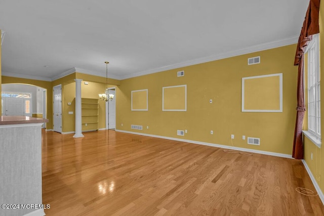 interior space featuring a chandelier, light hardwood / wood-style flooring, crown molding, and decorative columns