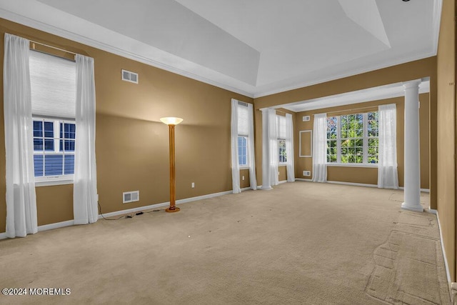 spare room featuring decorative columns, a raised ceiling, and light carpet