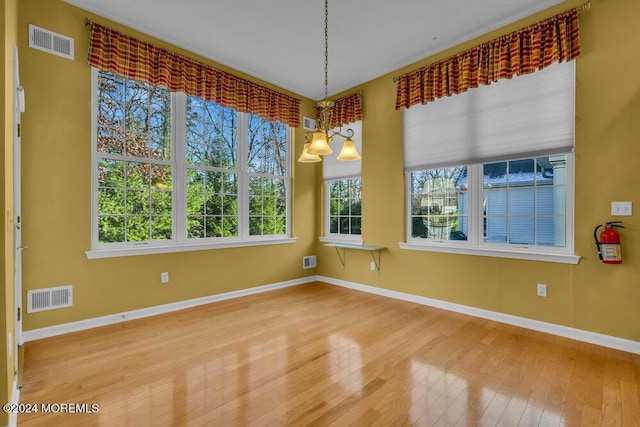 spare room featuring wood-type flooring and an inviting chandelier