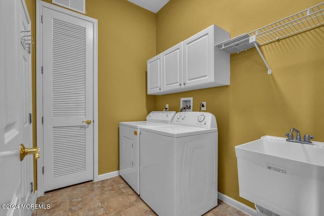 laundry area featuring cabinets, separate washer and dryer, and sink