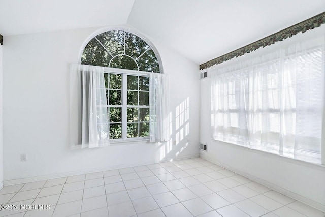 tiled empty room with lofted ceiling and a wealth of natural light