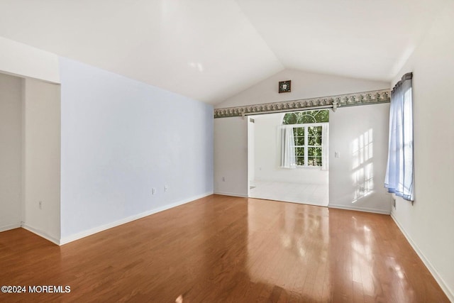 unfurnished room with hardwood / wood-style flooring and vaulted ceiling