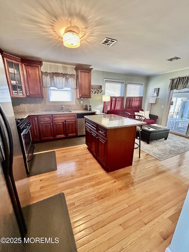 kitchen featuring light wood-type flooring, decorative backsplash, sink, and stainless steel appliances